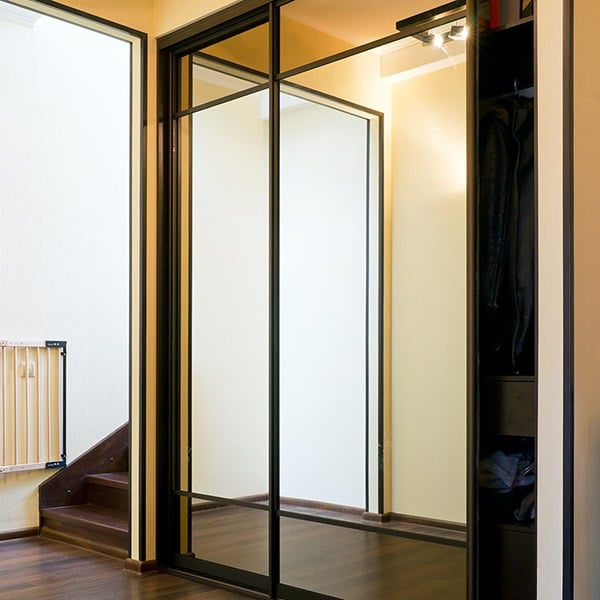 skyvedørsgarderobe med speil og svarte profiler og sprosser som dekor